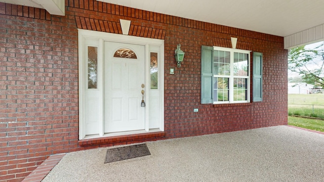 doorway to property with brick siding and a porch