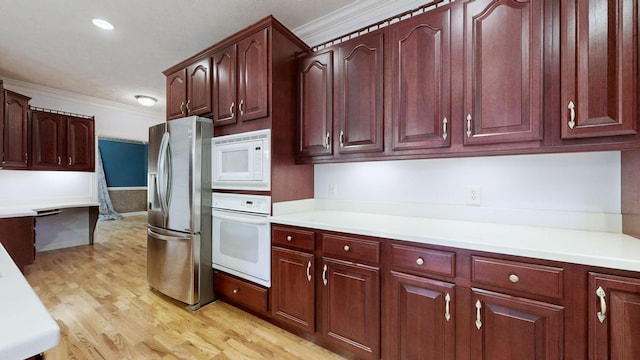 kitchen with ornamental molding, white appliances, light countertops, and light wood finished floors
