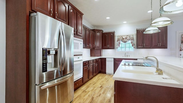 kitchen with a sink, light wood-style floors, white appliances, crown molding, and light countertops