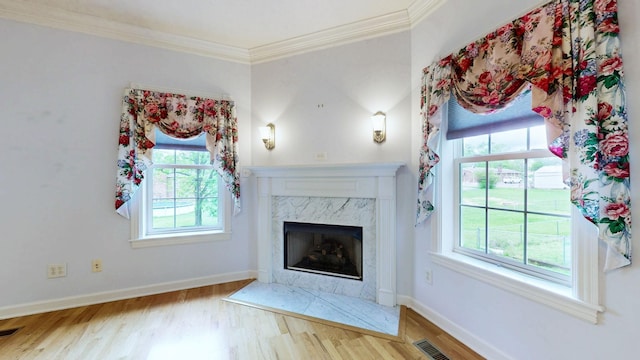 unfurnished living room featuring crown molding, wood finished floors, and a healthy amount of sunlight