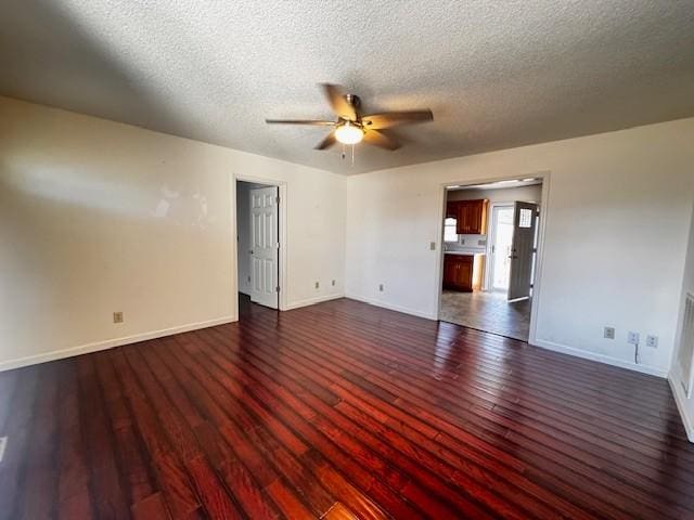 spare room featuring dark wood-type flooring, ceiling fan, and a textured ceiling