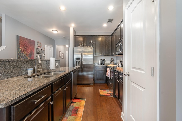 kitchen with stone counters, dark hardwood / wood-style floors, sink, dark brown cabinetry, and stainless steel appliances