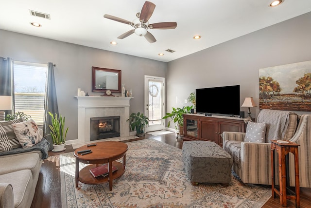 living room featuring hardwood / wood-style flooring, a tiled fireplace, and a healthy amount of sunlight