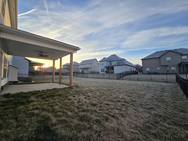 yard at dusk featuring a patio and ceiling fan