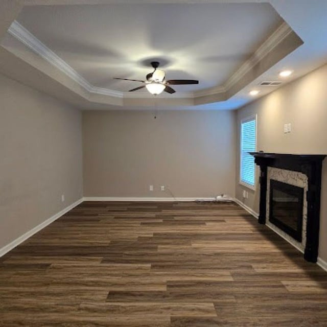 unfurnished living room with crown molding, ceiling fan, dark hardwood / wood-style flooring, and a tray ceiling