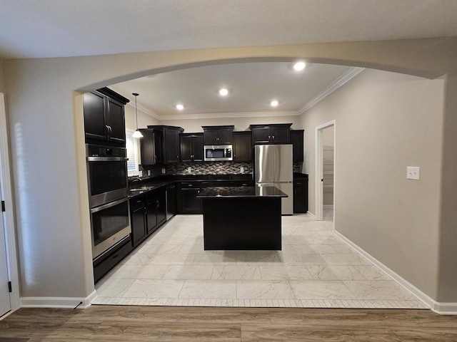 kitchen with appliances with stainless steel finishes, decorative light fixtures, sink, decorative backsplash, and a center island