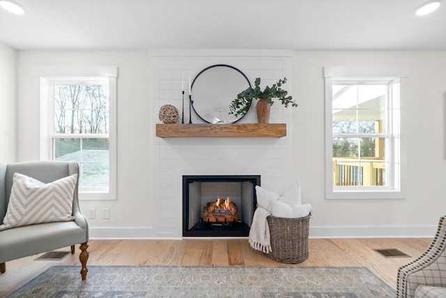 living area with light hardwood / wood-style floors and a large fireplace