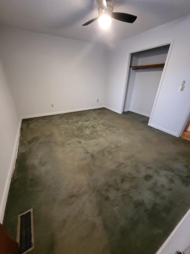 unfurnished bedroom featuring dark carpet, a ceiling fan, baseboards, visible vents, and a closet