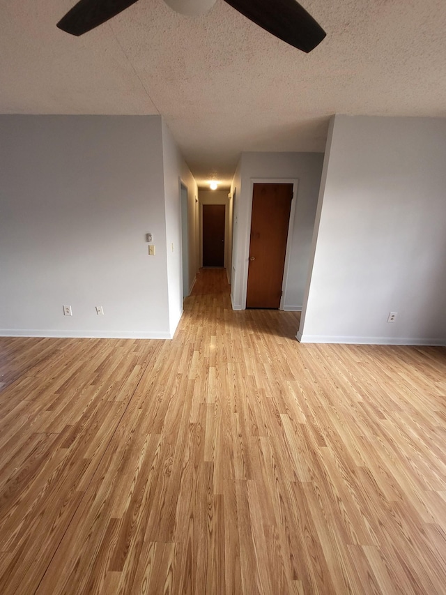 empty room featuring baseboards, a textured ceiling, ceiling fan, and light wood finished floors