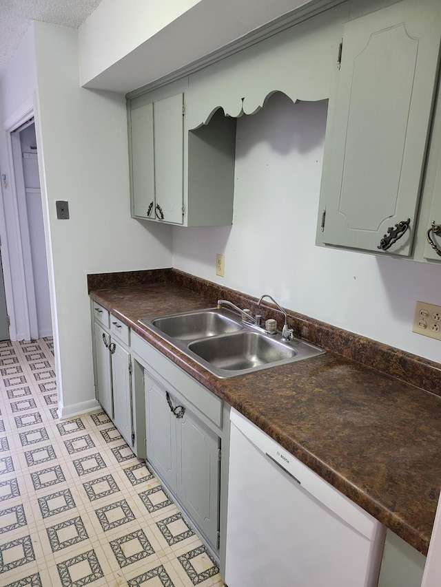 kitchen with a sink, light floors, dishwasher, and dark countertops