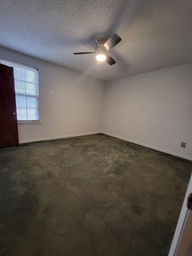 empty room with baseboards, ceiling fan, dark colored carpet, and a textured ceiling