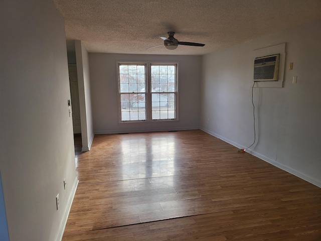 unfurnished room with a ceiling fan, a textured ceiling, a wall mounted AC, and wood finished floors