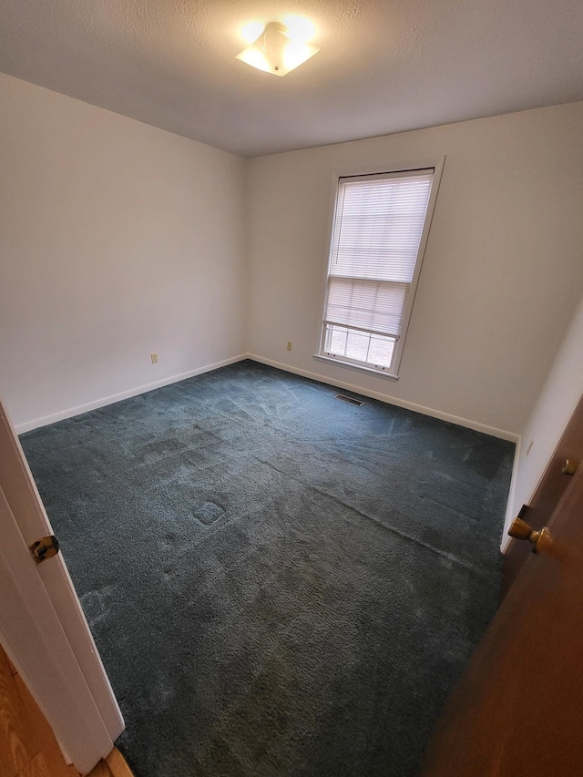 unfurnished room featuring baseboards, visible vents, and dark colored carpet