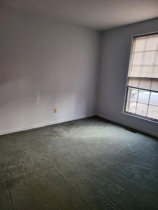 carpeted empty room featuring baseboards and visible vents