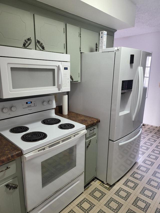 kitchen with dark countertops, a textured ceiling, and white appliances