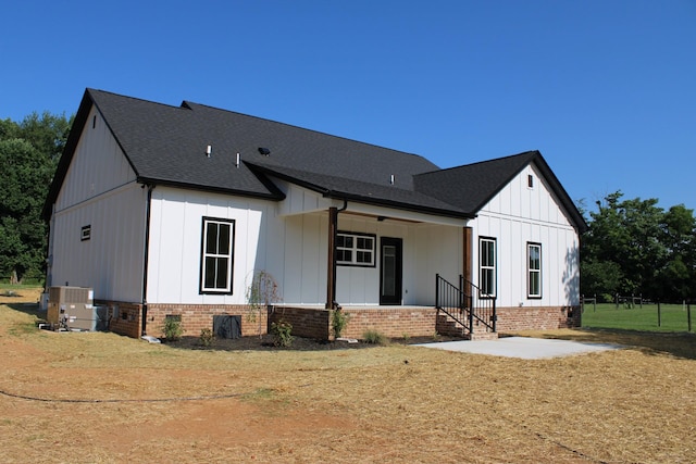 view of front of property featuring a porch, a front yard, and central AC unit