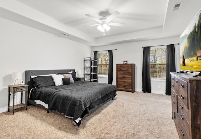 carpeted bedroom with ceiling fan and a tray ceiling