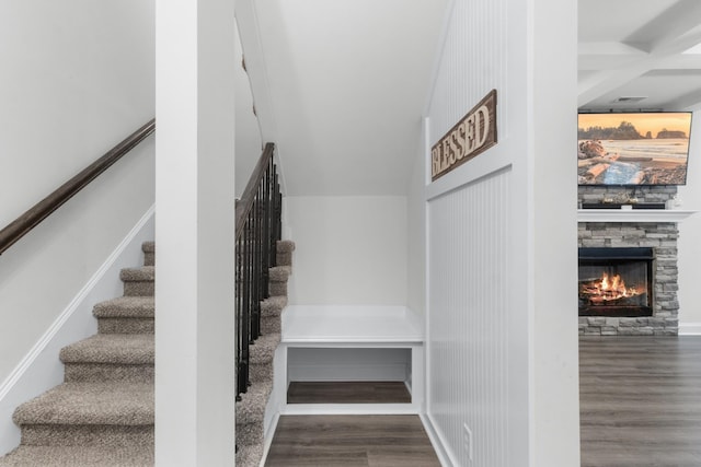 stairs with hardwood / wood-style flooring and a stone fireplace