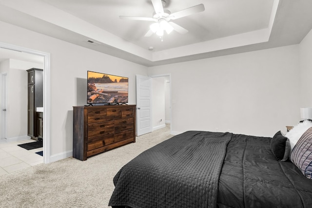 bedroom with ceiling fan, a raised ceiling, and light carpet