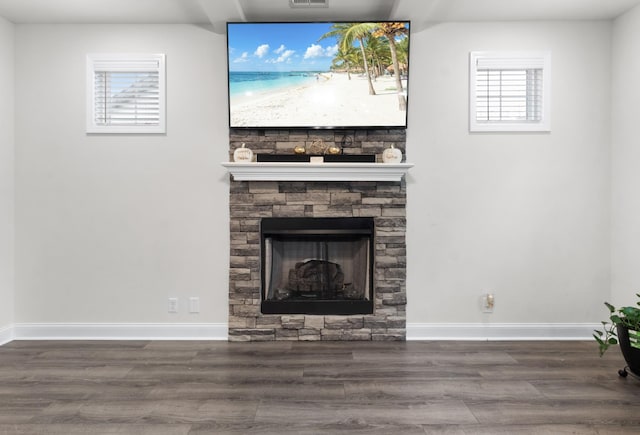 living room with dark hardwood / wood-style flooring and a stone fireplace