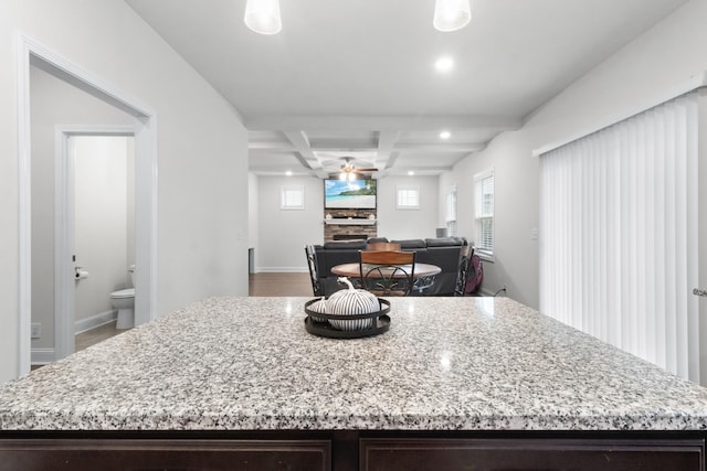 kitchen with a kitchen island, beamed ceiling, coffered ceiling, ceiling fan, and dark brown cabinets