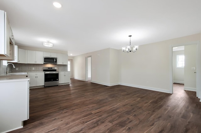 kitchen featuring sink, decorative light fixtures, appliances with stainless steel finishes, white cabinets, and backsplash