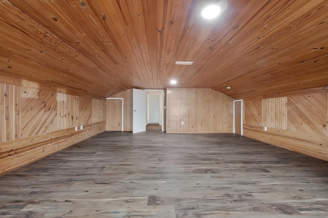 additional living space featuring lofted ceiling, wooden walls, and dark hardwood / wood-style flooring