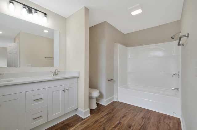 full bathroom with  shower combination, toilet, hardwood / wood-style floors, and vanity