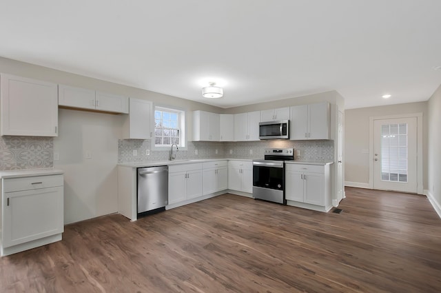 kitchen featuring white cabinetry, sink, backsplash, dark hardwood / wood-style flooring, and stainless steel appliances