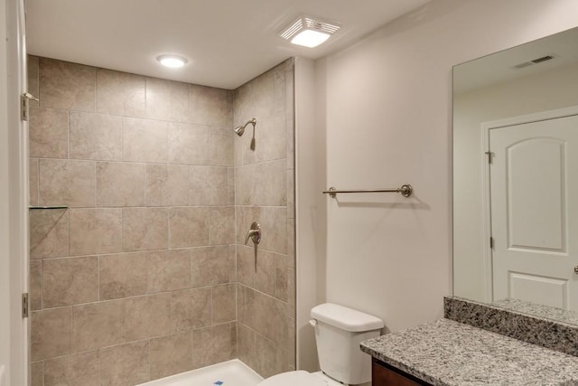 bathroom featuring tiled shower, vanity, and toilet