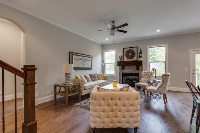 living room with crown molding, dark hardwood / wood-style floors, ceiling fan, and a fireplace