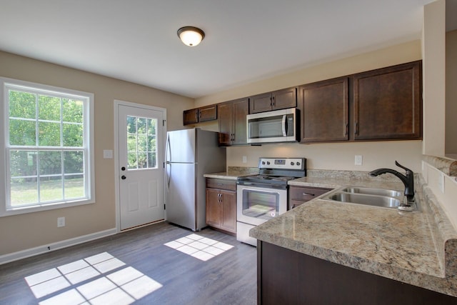 kitchen with stainless steel appliances, dark hardwood / wood-style flooring, sink, and dark brown cabinets