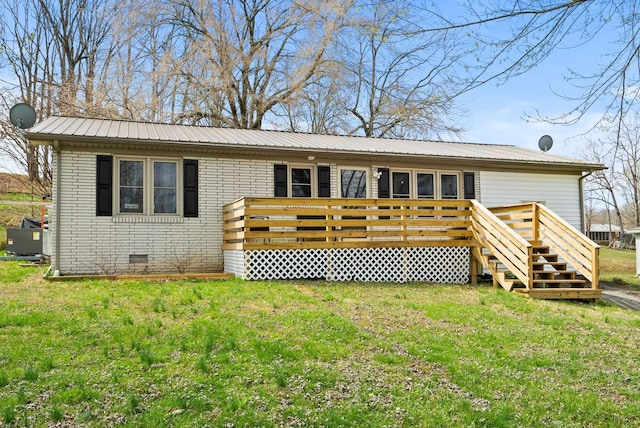 rear view of property featuring a wooden deck and a lawn