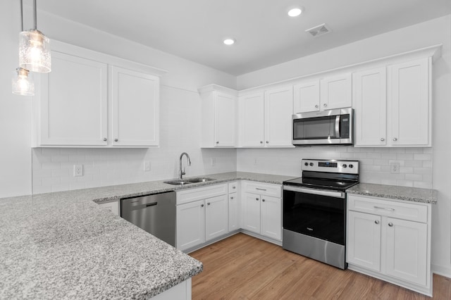 kitchen featuring sink, white cabinetry, hanging light fixtures, stainless steel appliances, and light wood-type flooring