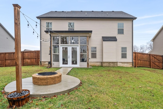 back of property with a yard, a fire pit, and french doors