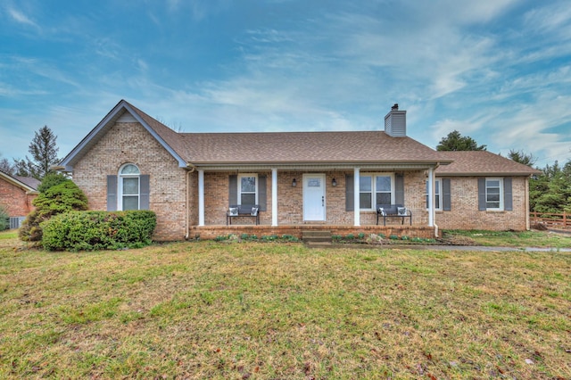 ranch-style house featuring covered porch and a front yard