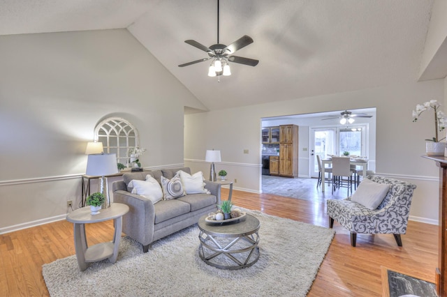 living room featuring ceiling fan, high vaulted ceiling, and light wood-type flooring