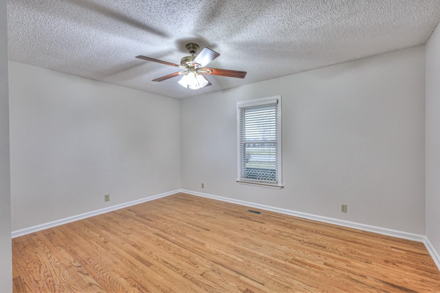 empty room with ceiling fan, a textured ceiling, and light hardwood / wood-style floors