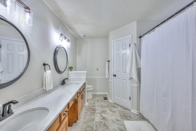 bathroom featuring vanity, a textured ceiling, and toilet