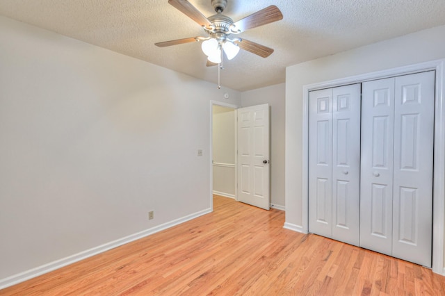 unfurnished bedroom featuring ceiling fan, a closet, light hardwood / wood-style floors, and a textured ceiling