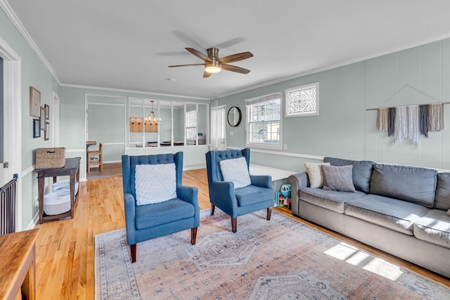 living room featuring ceiling fan with notable chandelier, wood-type flooring, and ornamental molding