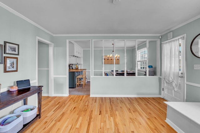 foyer with an inviting chandelier, ornamental molding, and light hardwood / wood-style floors