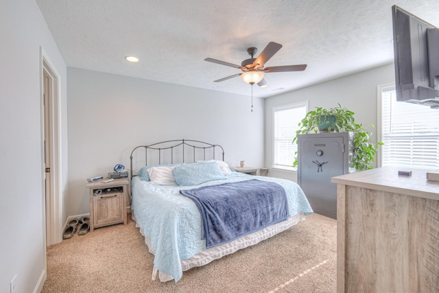 carpeted bedroom with ceiling fan and a textured ceiling