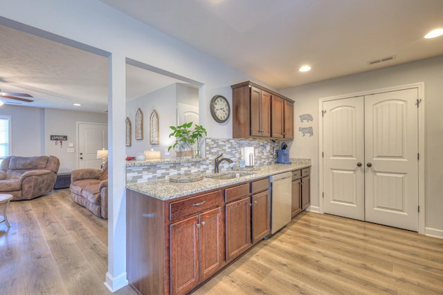 kitchen featuring dishwasher, light stone counters, decorative backsplash, light hardwood / wood-style floors, and sink