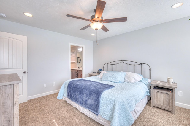 carpeted bedroom with ceiling fan, sink, ensuite bath, and a textured ceiling