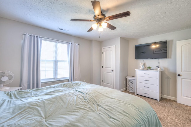 carpeted bedroom with ceiling fan and a textured ceiling