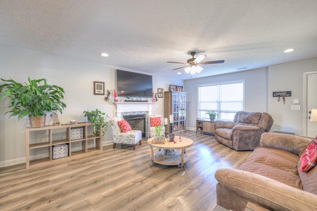 living room with hardwood / wood-style flooring, ceiling fan, and a textured ceiling