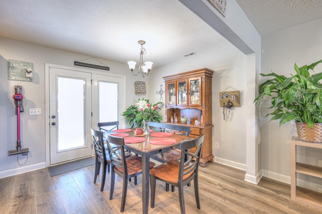 dining area featuring a textured ceiling, hardwood / wood-style floors, and a chandelier