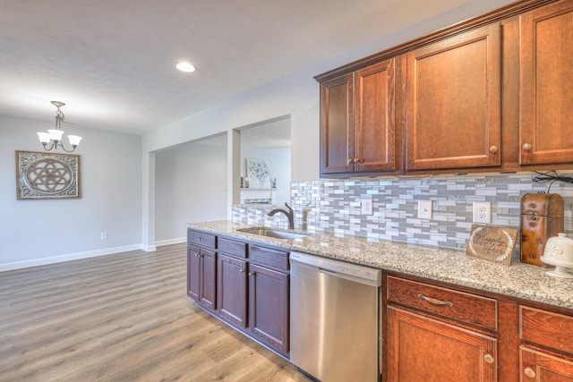 kitchen featuring tasteful backsplash, a chandelier, stainless steel dishwasher, a sink, and light wood-style flooring