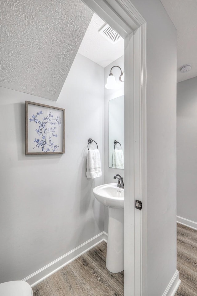 bathroom with baseboards, visible vents, and wood finished floors